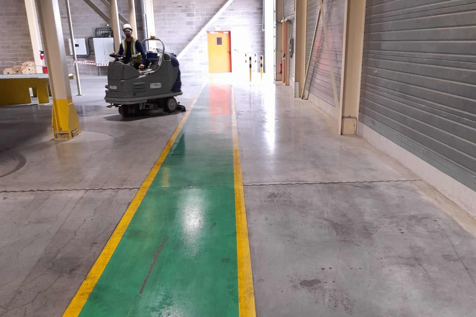 Opérateur ELnet lavant le sol d'un entrepôt industriel à l'autolaveuse autoportée
