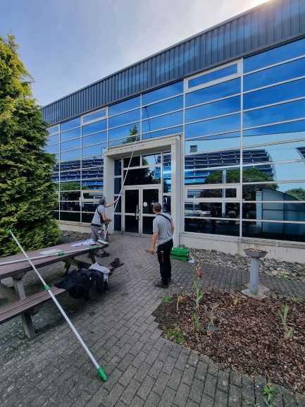 Deux agents ELnet nettoient la façade vitrée d'un bâtiment tertiaire